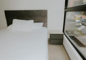 a bedroom with a white bed and a window at Apartamento moderno en Usaquen, con Coworking y a pasos de la Fundación Santa Fe in Bogotá
