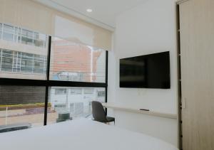 a bedroom with a large window and a tv on a wall at Apartamento moderno en Usaquen, con Coworking y a pasos de la Fundación Santa Fe in Bogotá