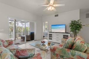 a living room with a couch and a flat screen tv at Halliday in Sanibel