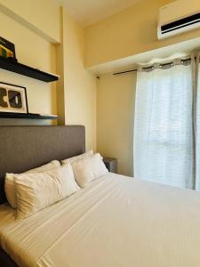 Un dormitorio con una cama blanca con una ventana. en Nature Lovers Paradise in Iloilo City - Cozy Condo Rental, en Iloilo City