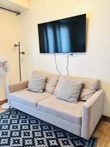 Un sofá en una sala de estar con un televisor de pantalla plana. en Nature Lovers Paradise in Iloilo City - Cozy Condo Rental, en Iloilo City