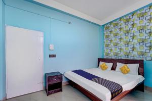 Un dormitorio con una cama con una pared azul. en Hotel O Home Trimurti guest house, en Guwahati