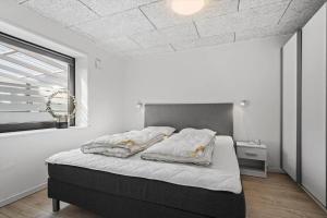 een slaapkamer met een bed in een witte kamer bij 8811-Hvide-Sande-Vesterhavsvej-3-stuen in Hvide Sande