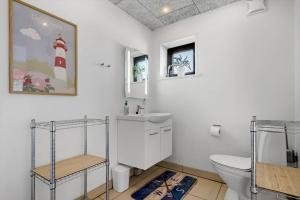 een witte badkamer met een wastafel en een toilet bij 8811-Hvide-Sande-Vesterhavsvej-3-stuen in Hvide Sande +25 foto's