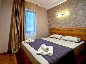a bedroom with a bed with towels and a window at Cottage "Soulmate" in Ambrolauri