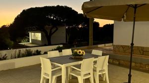 a wooden table with white chairs and an umbrella at Casa do Monte by Check-in Portugal in Albufeira