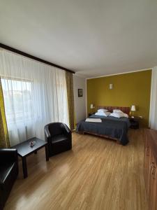 a hotel room with a bed and a chair at Helen Rooms Vama Veche in Vama Veche
