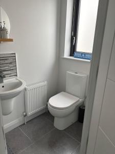 a white bathroom with a toilet and a sink at The Nineteenth at Portstewart in Portstewart