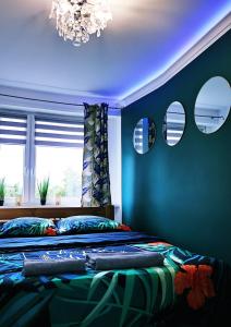 a bedroom with a bed with blue walls and a chandelier at Apartament Green Mrągowo-Mazury,blisko plaża, centrum! Wi-fi! in Mrągowo