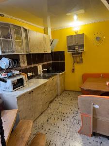 a kitchen with yellow walls and white cabinets and a table at Rumb116 in Odesa