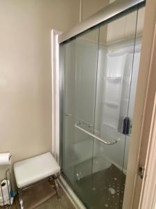 een glazen douche met een stoel in de badkamer bij Misty falls in Ormond Beach