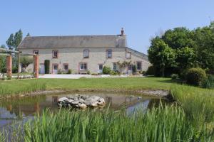 an old stone house with a pond in front of it at Ferme les Chapelles Utah Beach in Angoville-au-Plain