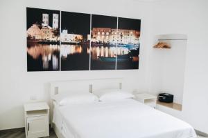 una camera da letto con un letto bianco e un quadro sul muro di Casa Del Capitano - Appartamento Accogliente - Molfetta a Molfetta