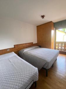Un dormitorio con dos camas y una ventana. en Montiva - The Green Lodge, en Asiago