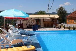 Un grupo de sillas y sombrillas junto a una piscina. en Pavlovica konaci, en Kotraža