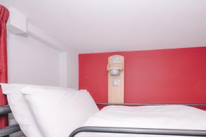 a bedroom with a red wall with a bed and a red wall at Astor Oxford Street in London +37 photos