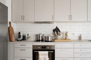 a kitchen with white cabinets and a stove with pots and pans at Bright Ground Floor Corner Home with Cozy Outdoor in Båstad