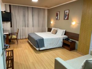 Una habitación de hotel con una cama grande y un escritorio. en City Hotel- Orla do Guaíba, Parque Harmonia, Mercado Público, en Porto Alegre