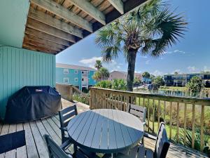 a table and chairs on a deck with a palm tree at Coconuts Beach House in Pensacola Beach