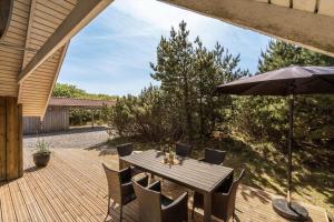 a wooden deck with a table and an umbrella at 072-Ringkobing-Sivsangervej-11 in Ringkøbing
