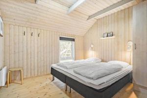 a bedroom with a bed in a room with wooden walls at 072-Ringkobing-Sivsangervej-11 in Ringkøbing