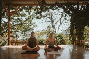 a man and woman sitting on the floor in meditation at Casa Awänímä - Luxury Permaculture Hotel & Eco-Retreat in Tzununá
