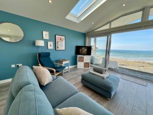 Una sala de estar con un sofá azul y un televisor. en Seaside Getaway with Balcony & Ocean Views - Westward Ho!, en Westward Ho