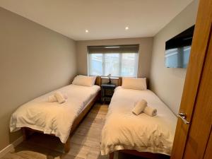 Dos camas en una habitación pequeña con ventana. en Seaside Getaway with Balcony & Ocean Views - Westward Ho!, en Westward Ho