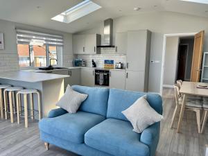 Una sala de estar con un sofá azul y una cocina. en Seaside Getaway with Balcony & Ocean Views - Westward Ho!, en Westward Ho 18 fotos más