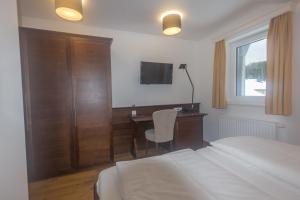 阿特湖畔翁特拉赫Hotel Stadler am Attersee的一间卧室，配有一张床、一张书桌和一台电视