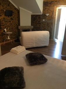 um quarto com uma cama branca e uma parede de tijolos em Casas do Terreiro em Seia