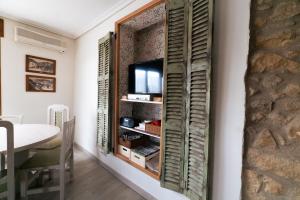 a room with a tv and a wall with wooden shutters at La Posadica Casa Aldabe in San Martín de Unx