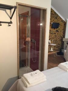 uma casa de banho com chuveiro e toalhas na cama em Casas do Terreiro em Seia mais 37 fotografias