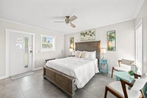 a white bedroom with a bed and a chair at The Banana River Resort in Cocoa Beach