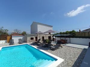 a swimming pool with chairs and umbrellas on a patio at Holiday Home Latin in Peruški