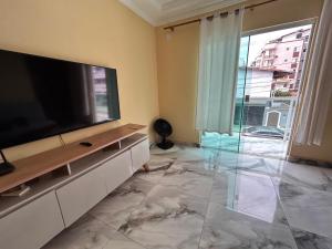 een woonkamer met een flatscreen-tv en een groot raam bij Apê Dunas do Forte in Cabo Frio
