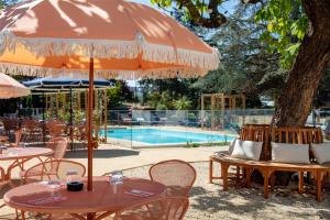a table with an umbrella next to a pool at Best Western Porte du Forez in Andrézieux-Bouthéon