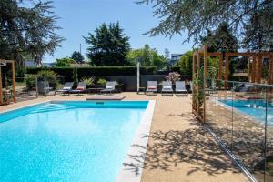 a swimming pool in a yard with lounge chairs at Best Western Saint-Etienne Porte du Forez in Andrézieux-Bouthéon