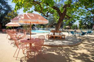 a group of tables and chairs under an umbrella next to a pool at Best Western Porte du Forez in Andrézieux-Bouthéon