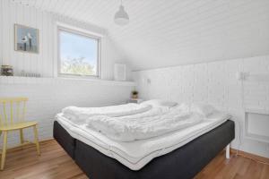 een groot bed in een witte kamer met een raam bij 2250-Ringkobing-Vestklitvej-25 in Klegod