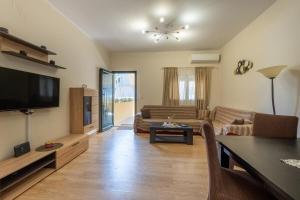 a living room with a couch and a tv at Vasilis Family House in Ágios Rókkos