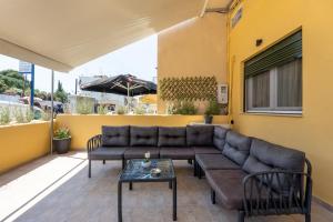 a patio with a couch and chairs and an umbrella at Vasilis Family House in Ágios Rókkos