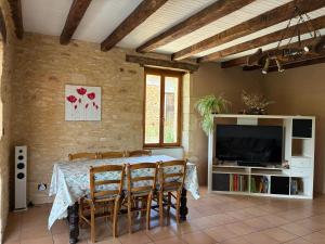 a dining room with a table and chairs and a television at Gîte de charme La Pradelle in Prats-du-Périgord