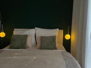 une chambre avec un lit aux murs verts et des oreillers dans l'établissement Designerwohnung mit malerischer Terrasse - Modern, Gemütlich & Zentral, à Hochheim am Main 1 autre photo