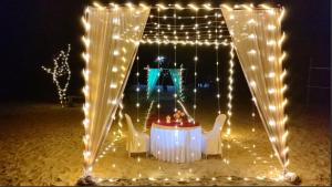 MāvalliNestle Sahayadri Beachfront Murudeshwar的带灯的帐篷前的一张桌子和几把椅子