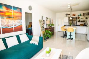 a living room with a green couch and a kitchen at Ocean Sunset Retreat in Philipsburg