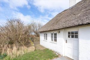 a white cottage with a thatched roof and a door at 315-Hvide-Sande-Holmsland-Klitvej-115-vest in Hvide Sande
