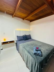 a bedroom with a bed with a pair of shoes on it at Loft encantador D - 8 km de Floripa in São José