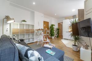 Una sala de estar con un sofá azul y una cocina. en Superior Deluxe Apartment - Premium Malaga Center, en Málaga