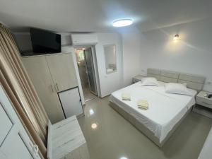 a white bedroom with a bed and a television at Cazare Pedro in Mamaia